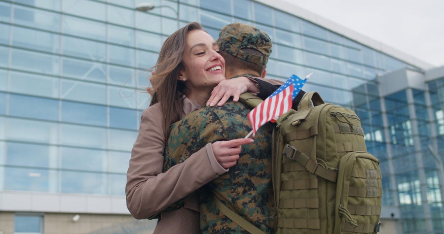 Military service member hugging family